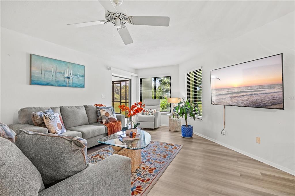 A living room features a gray sectional sofa, a glass coffee table, and a wall-mounted television — 792 CAPRI ISLE BLVD UNIT 134, VENICE, FL