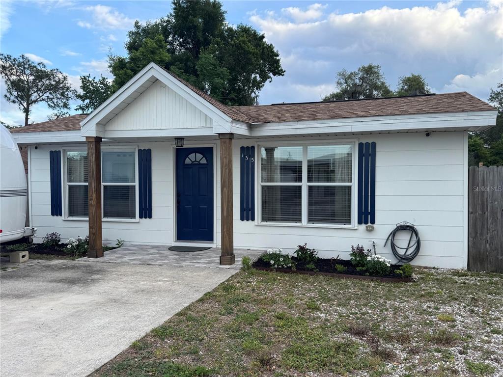 A white single-story house features a blue front door, wooden porch posts, and blue shutters — 135 CARROLL STREET, CLERMONT, FL