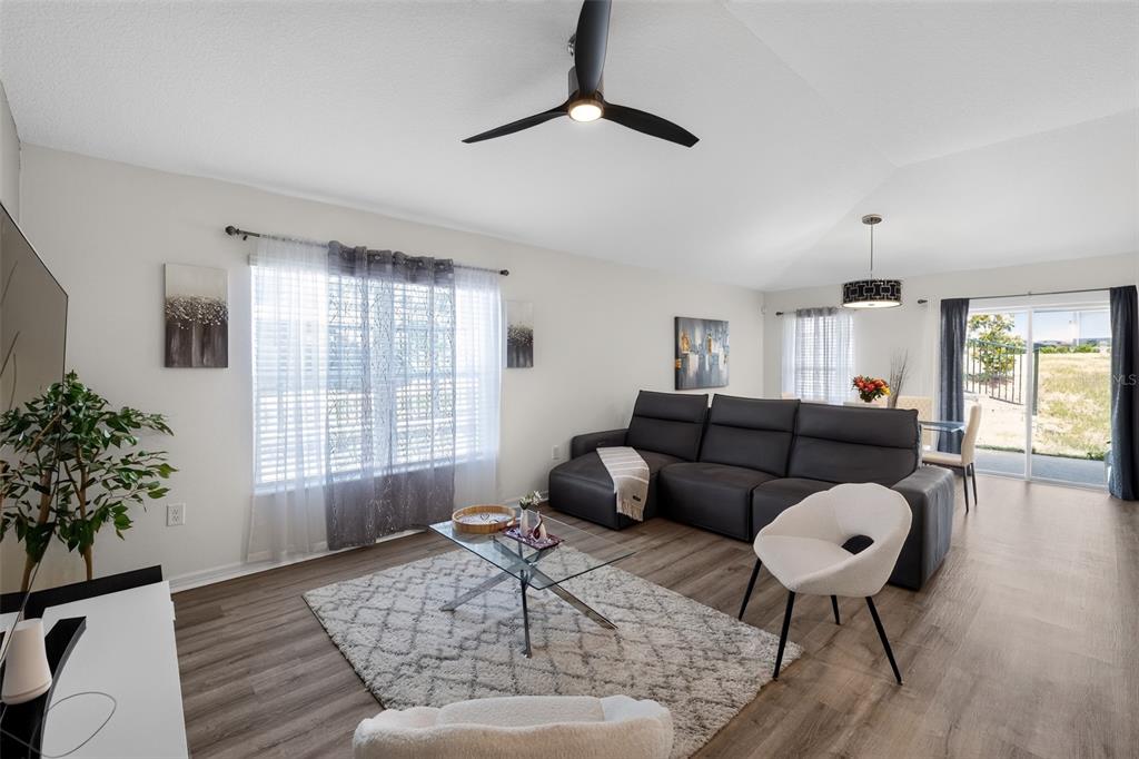 A living room with a gray sectional, white accent chairs, and a glass coffee table — 9181 OSCRAFT DRIVE, DAVENPORT, FL