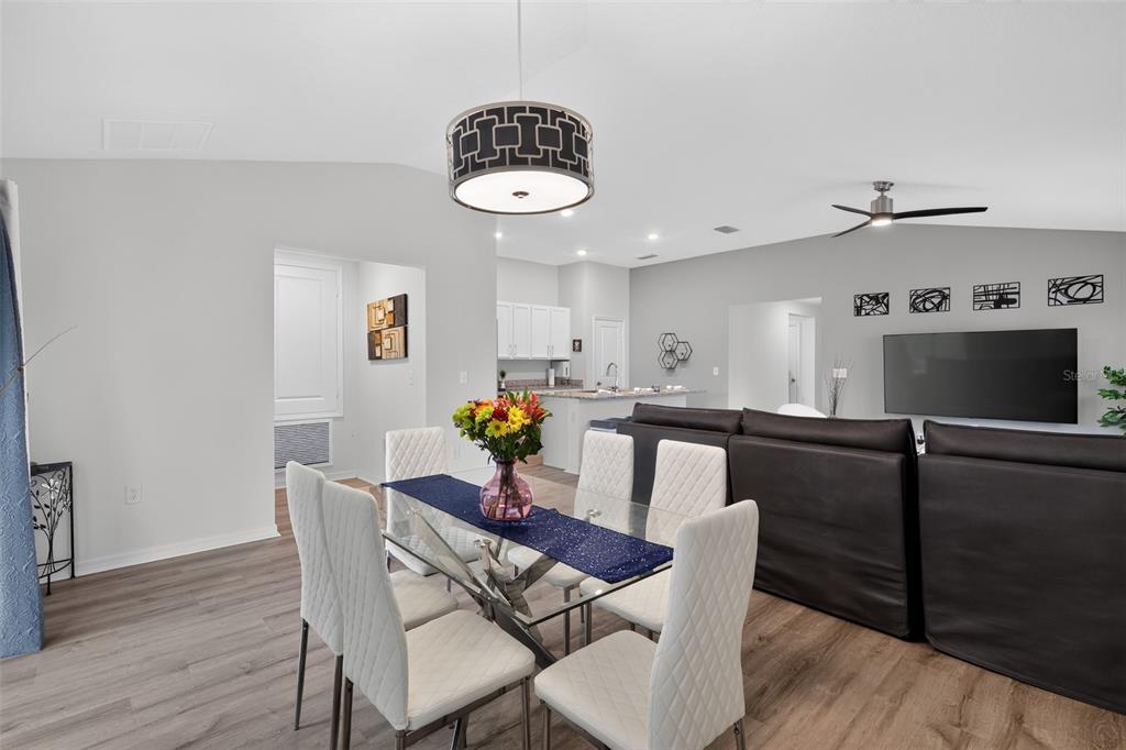 A dining area with a glass table and white chairs opens into a living room — 9181 OSCRAFT DRIVE, DAVENPORT, FL