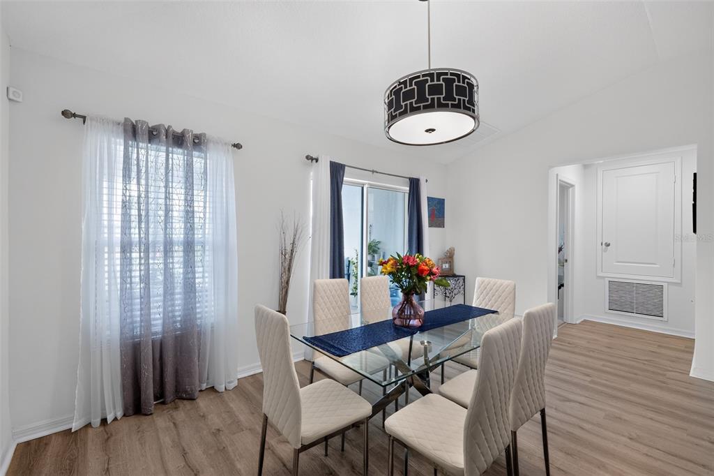 A dining room features a glass table with six upholstered chairs under a patterned pendant light — 9181 OSCRAFT DRIVE, DAVENPORT, FL