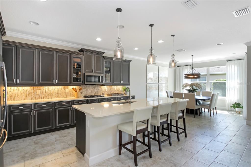 A kitchen with dark cabinets, a large white island, and an adjacent dining area — 138 OLD MOSS CIRCLE, DELAND, FL