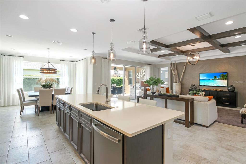 A kitchen island with a sink sits in front of an open dining and living area — 138 OLD MOSS CIRCLE, DELAND, FL