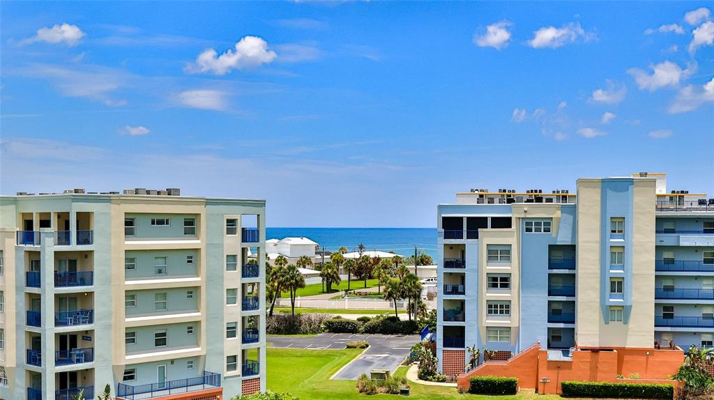 An elevated exterior view shows two multi-story apartment buildings overlooking a beach and ocean — 5300 S ATLANTIC AVENUE UNIT 5601, NEW SMYRNA BEACH, FL