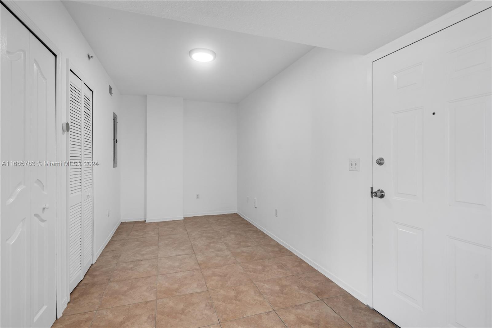 A small, empty room features white walls, a tiled floor, and two white doors — 218 NW 12th Ave # 702, Miami FL 33128, MIAMI, FL