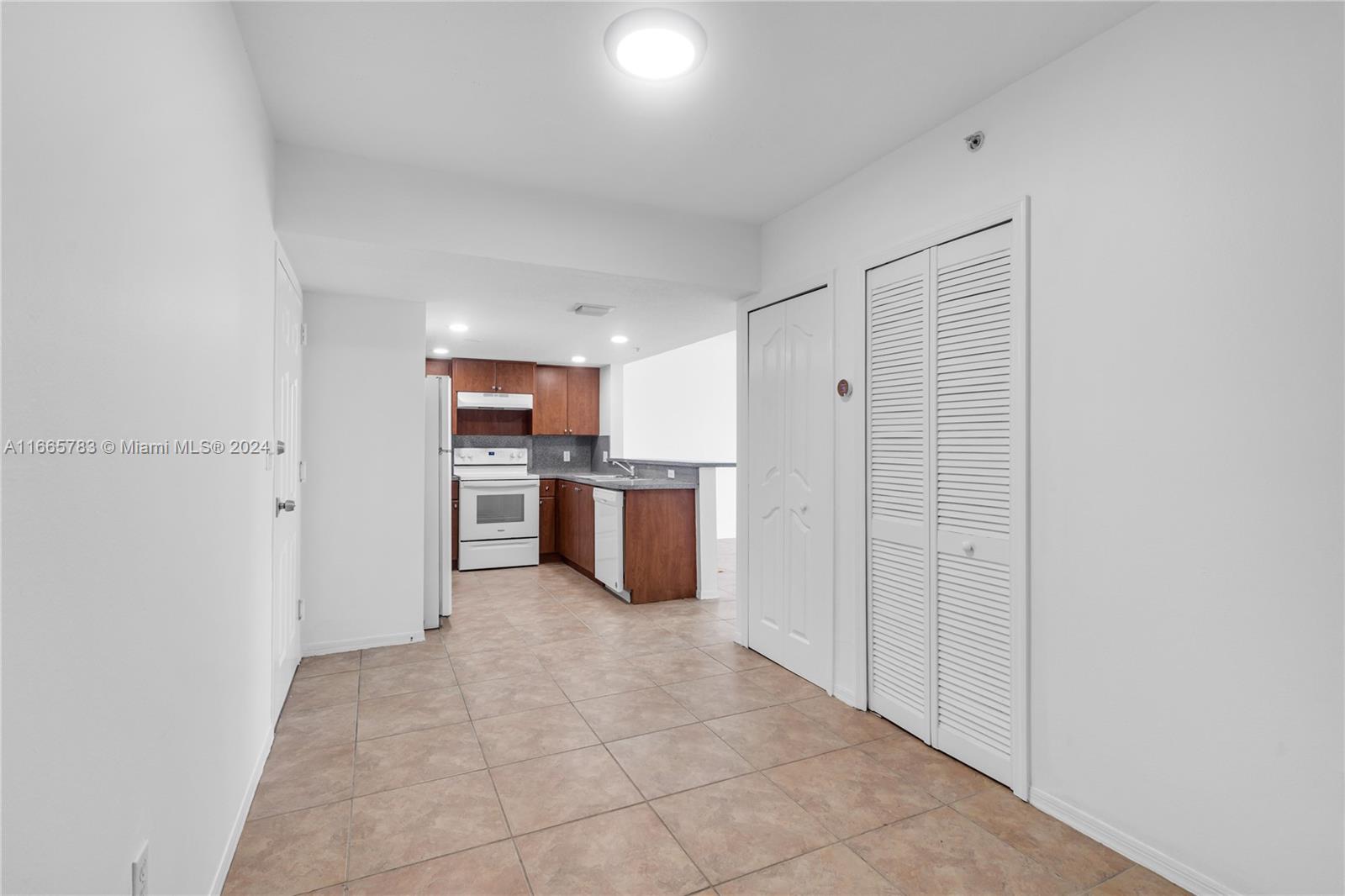 A tiled entryway leads to a kitchen with wood cabinets and white appliances — 218 NW 12th Ave # 702, Miami FL 33128, MIAMI, FL
