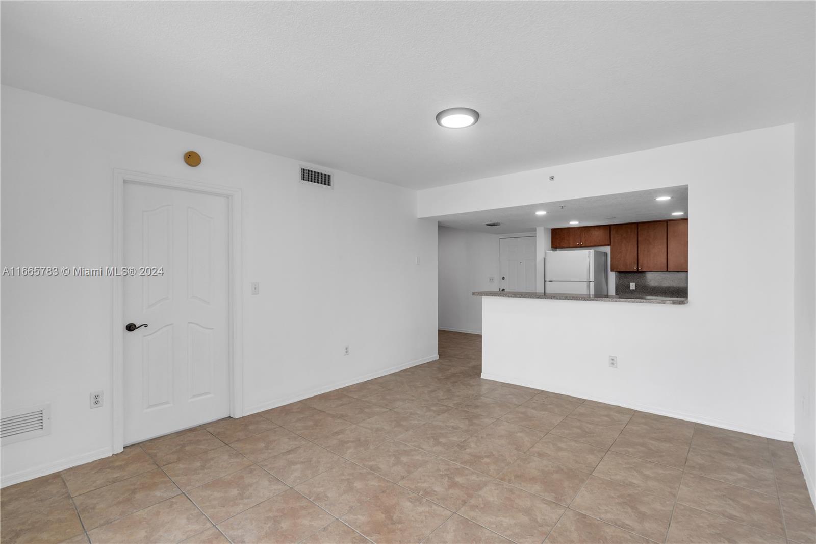 An unfurnished room with tile flooring features a kitchen pass-through and a white door — 218 NW 12th Ave # 702, Miami FL 33128, MIAMI, FL