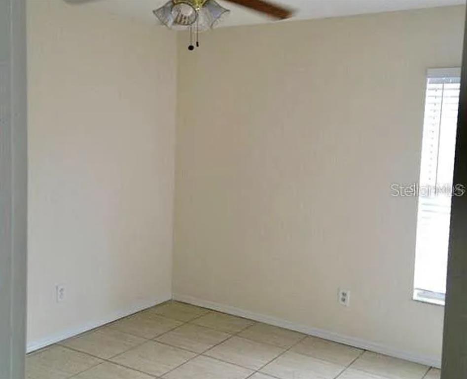 A small, empty room features beige walls, light-colored floor tiles, and a ceiling fan — 13706 GLASSER AVENUE, ORLANDO, FL