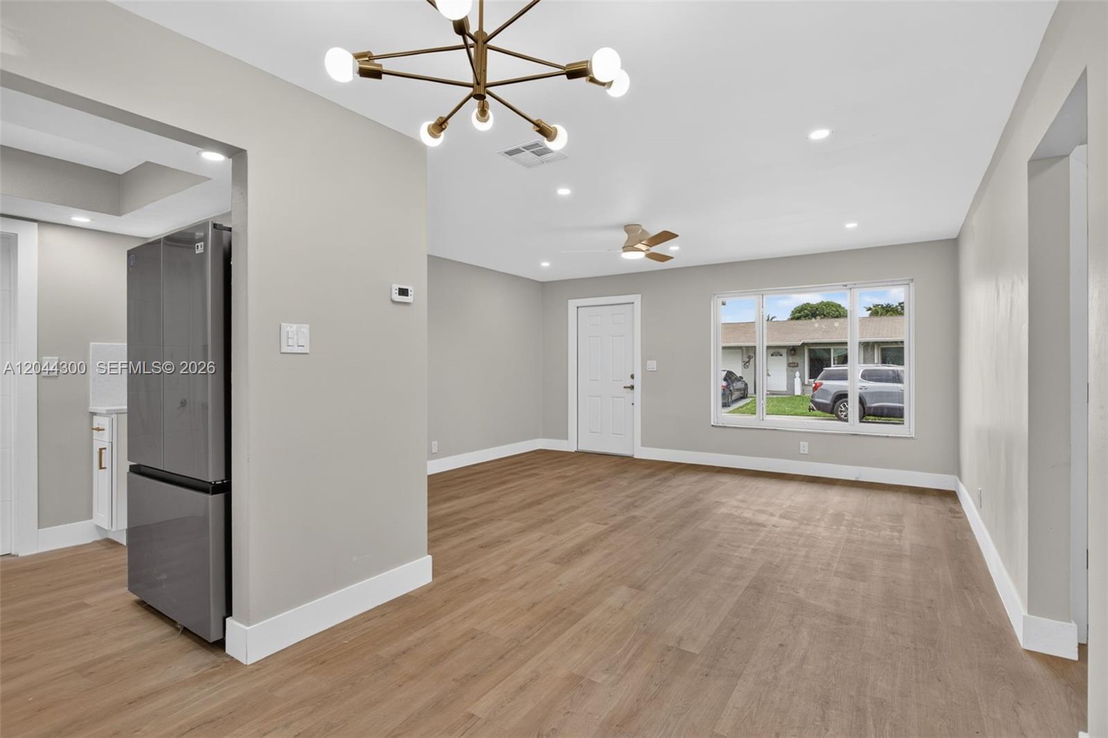 This room features light wood-look flooring, a modern chandelier, and a large window — 5711 NW 48th Ter, Tamarac FL 33319, TAMARAC, FL