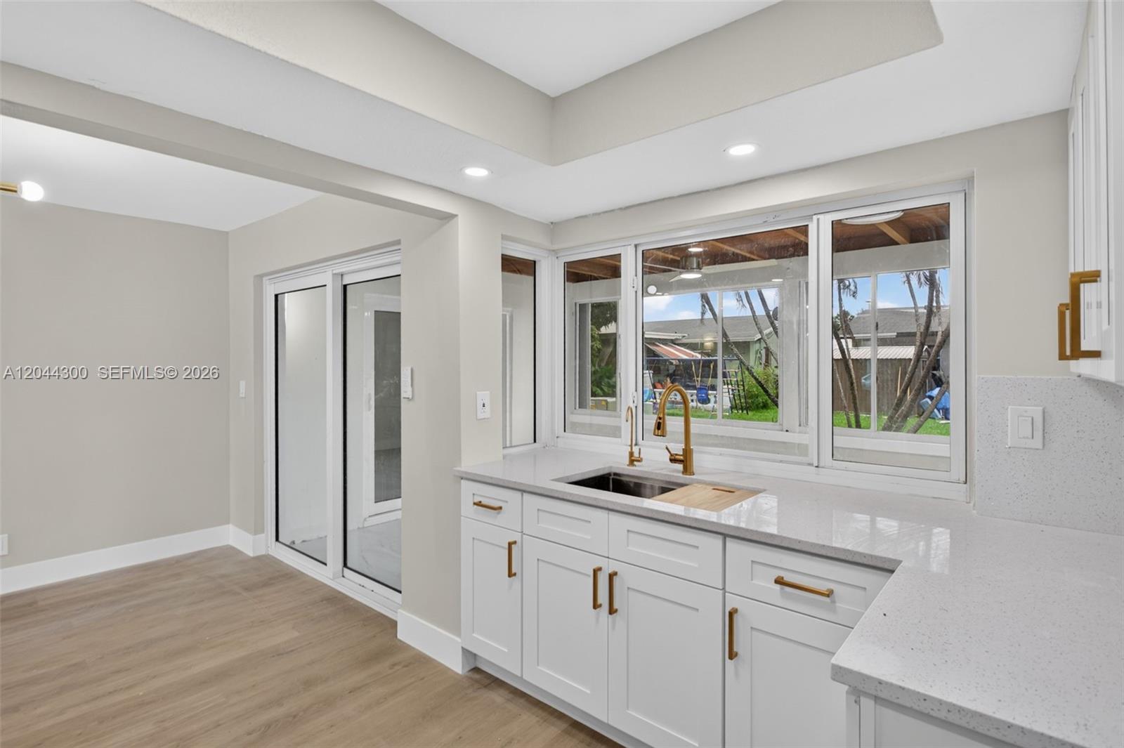 A kitchen features white cabinets, quartz countertops, a gold faucet, and a large window — 5711 NW 48th Ter, Tamarac FL 33319, TAMARAC, FL