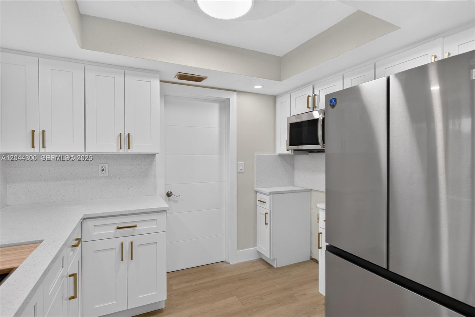 A kitchen features white cabinets, stainless steel appliances, and light-colored countertops — 5711 NW 48th Ter, Tamarac FL 33319, TAMARAC, FL