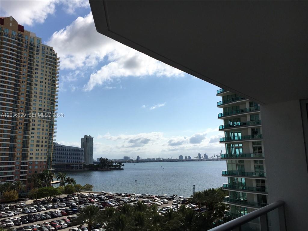 A bedroom features a white bed, patterned bedding, and a sliding glass door to a balcony — 1300 Brickell Bay Dr # 710, Miami FL 33131, MIAMI, FL