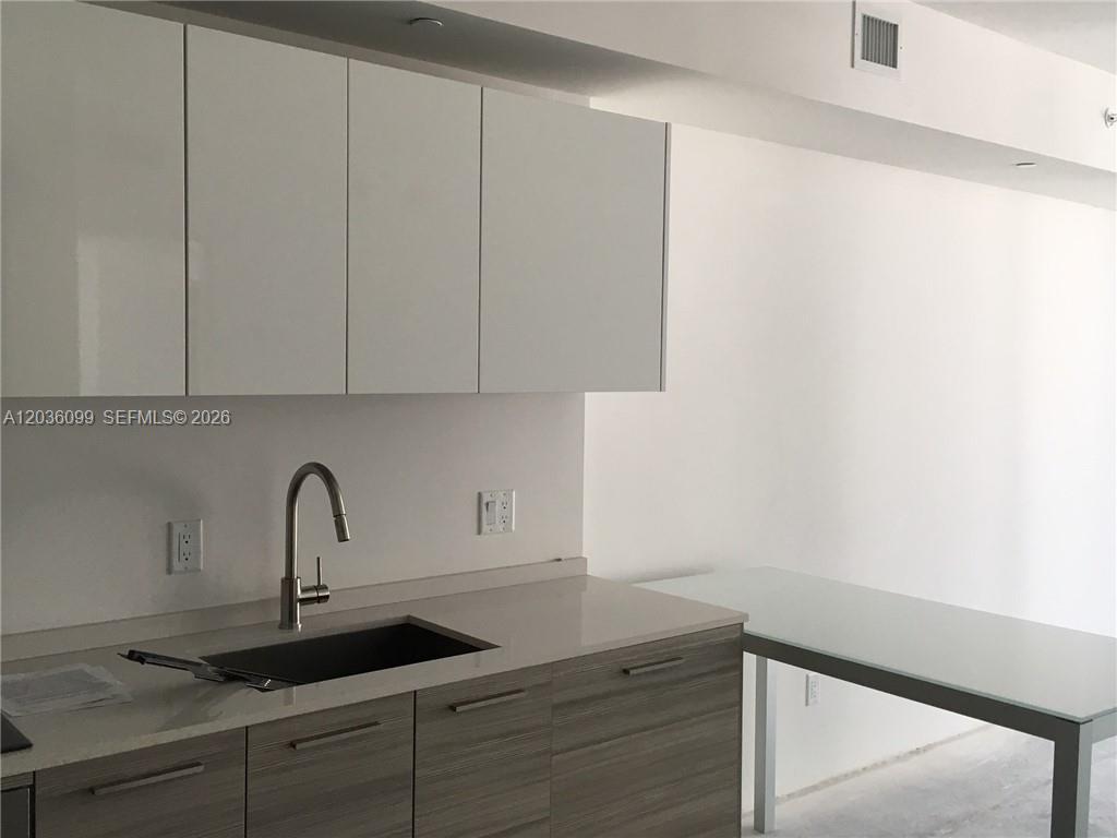 A bright living room features a white sofa, glass coffee table, and a wall-mounted television — 1300 Brickell Bay Dr # 710, Miami FL 33131, MIAMI, FL