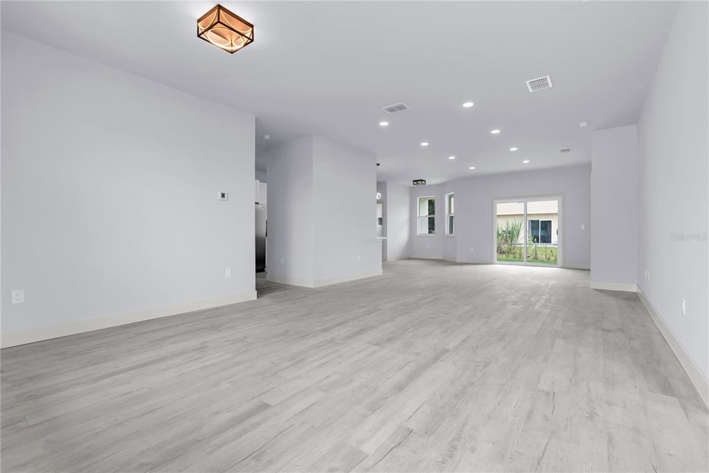 An open-concept living area features light gray wood-look flooring, recessed lighting, and sliding glass doors — 965 NANCY COURT, KISSIMMEE, FL