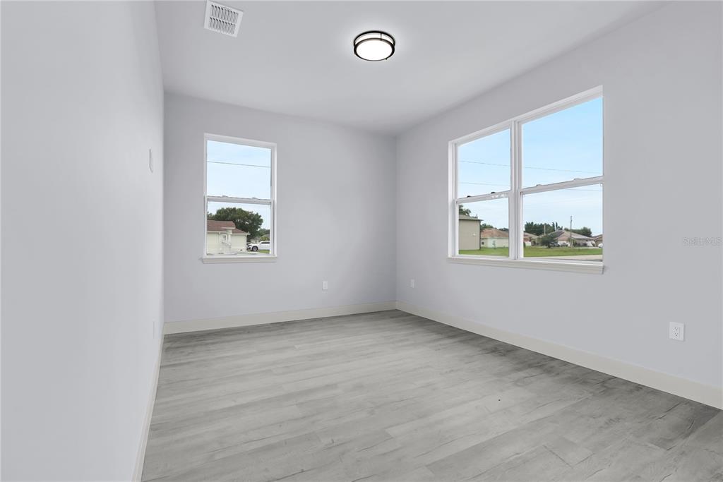 An empty room with light gray walls, wood-look flooring, and two windows — 965 NANCY COURT, KISSIMMEE, FL