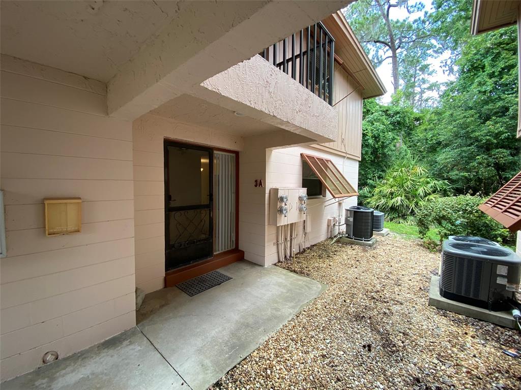 The exterior of a two-story building features a concrete patio, a screen door, and HVAC units — 160 LIVE OAK WOODS COURT UNIT 3A, DELTONA, FL