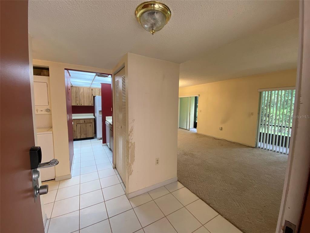 An entryway with tiled floors leads to a carpeted living area and a small kitchen — 160 LIVE OAK WOODS COURT UNIT 3A, DELTONA, FL