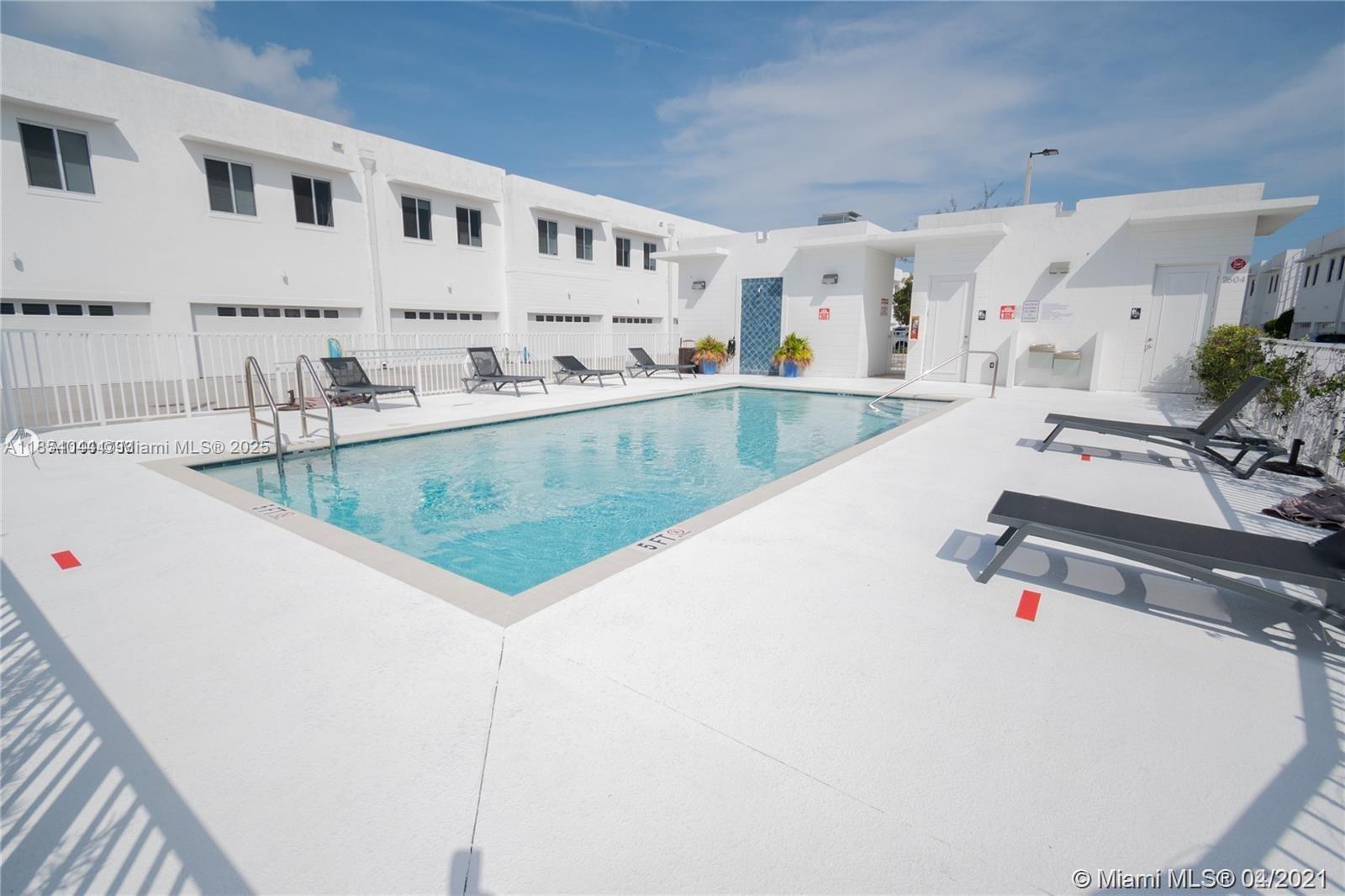 A rectangular swimming pool is surrounded by a white deck with lounge chairs — 2651 NE 212th Ter # 103, Miami FL 33180, MIAMI, FL