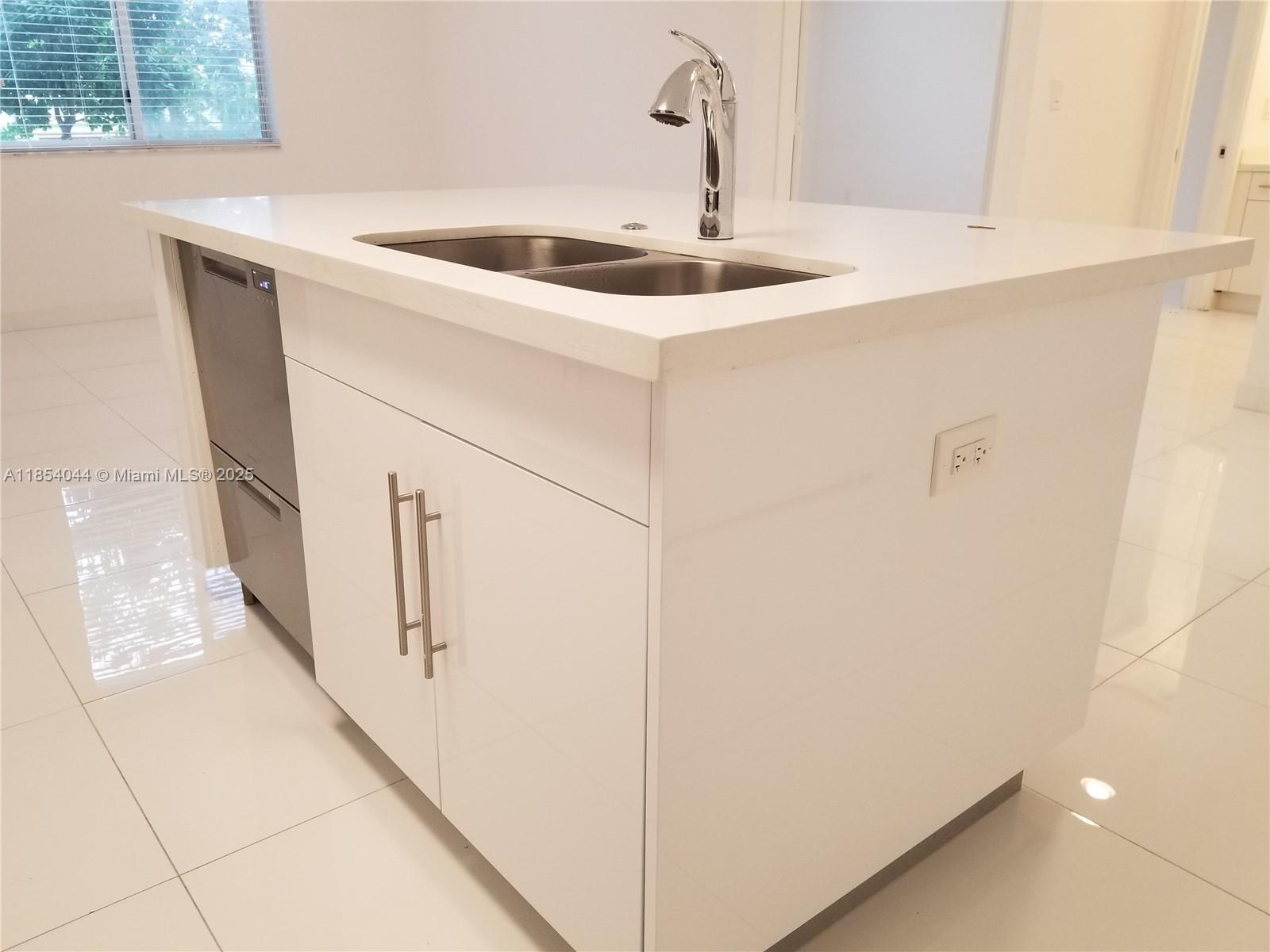A white kitchen island features a stainless steel sink, faucet, and built-in dishwasher — 2651 NE 212th Ter # 103, Miami FL 33180, MIAMI, FL