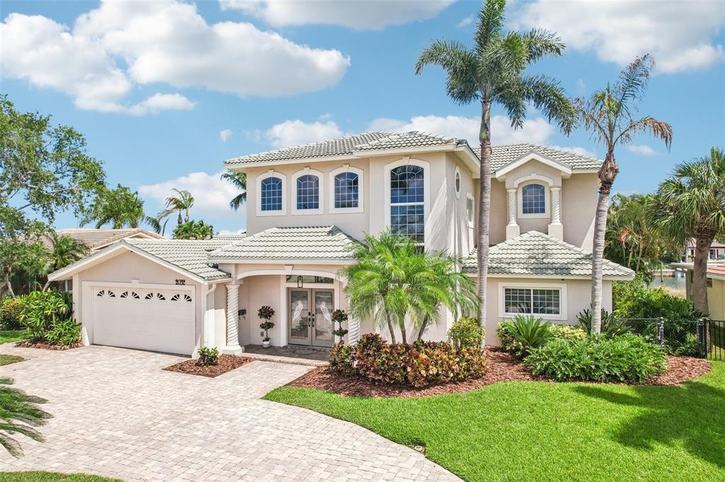 A two-story stucco house with a tiled roof, palm trees, and a paved driveway — 2032 MASSACHUSETTS AVENUE NE, ST PETERSBURG, FL