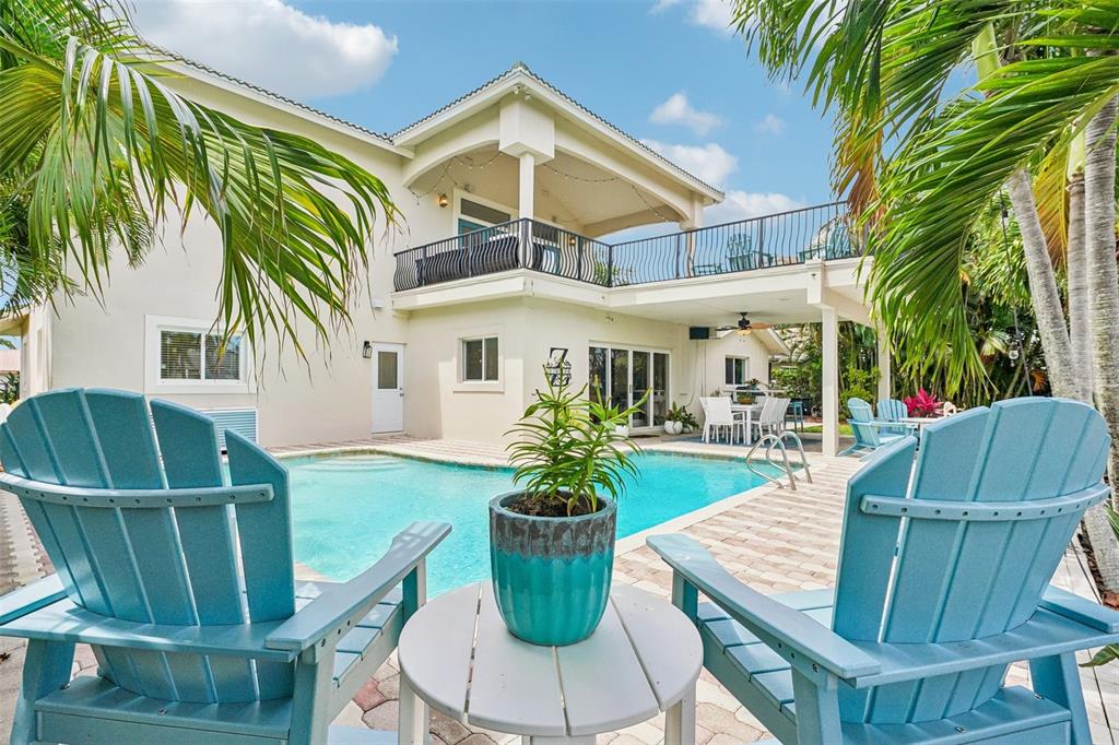 A backyard swimming pool sits in front of a two-story house with a balcony — 2032 MASSACHUSETTS AVENUE NE, ST PETERSBURG, FL