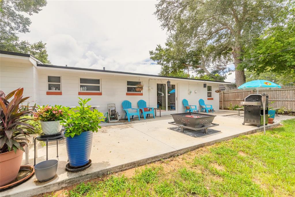 A concrete patio features a fire pit, blue chairs, a grill, and potted plants — 1245 ESSEX ROAD, DAYTONA BEACH, FL