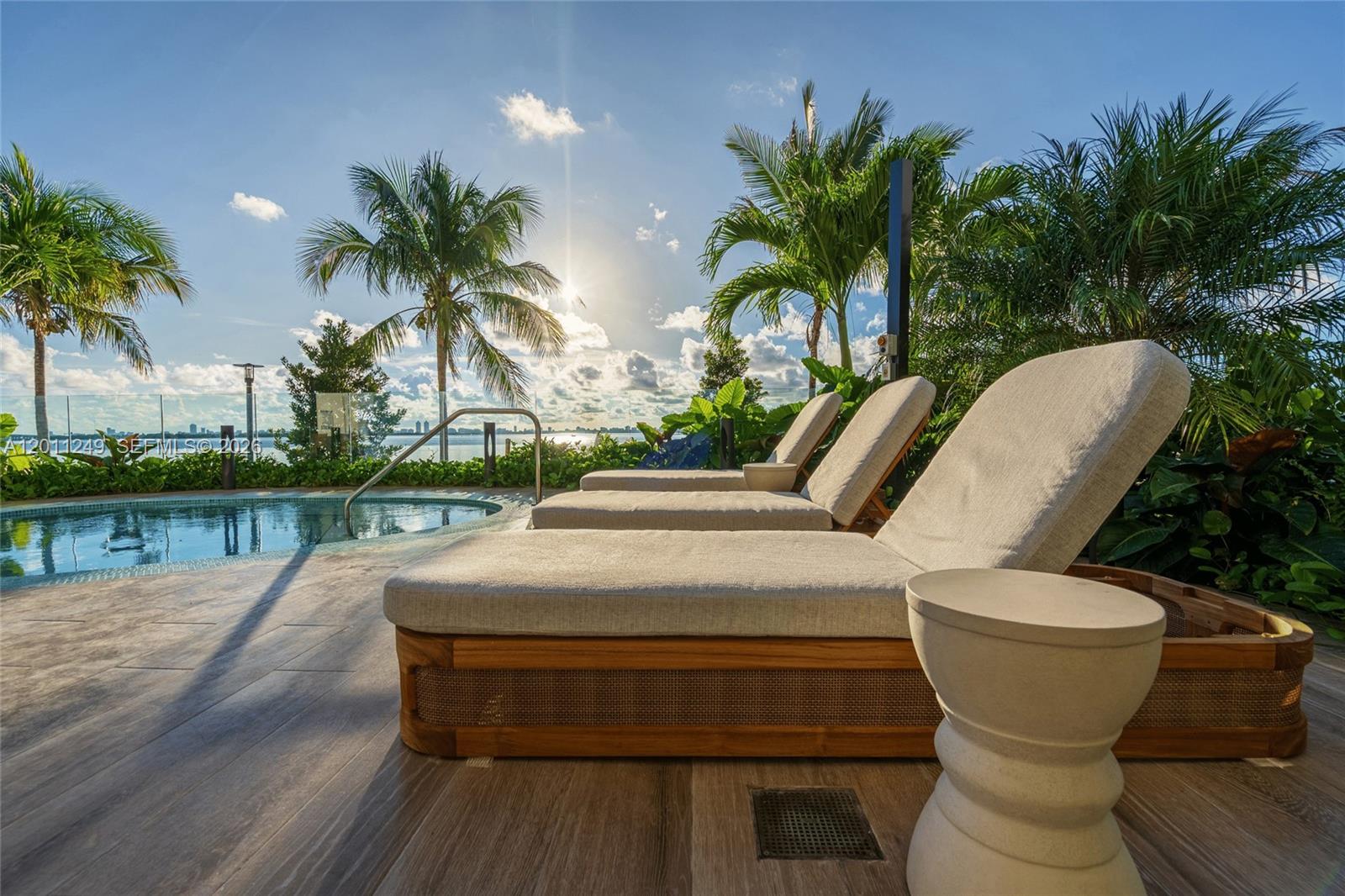 Three lounge chairs sit on a wooden pool deck next to a swimming pool outdoors — 725 NE 24th St # 301, Miami FL 33137, MIAMI, FL