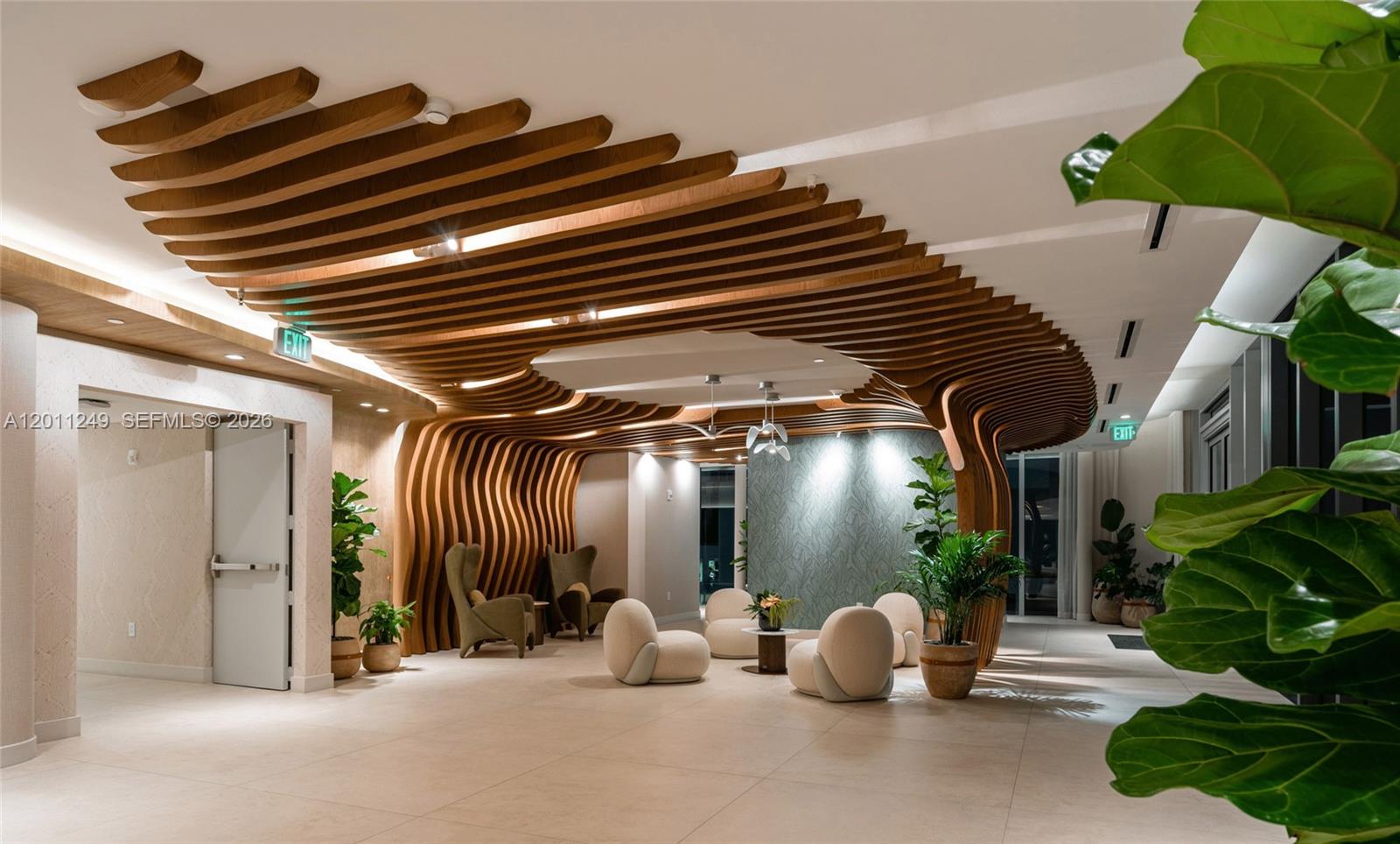 A modern lobby features a prominent wooden slat ceiling structure, tile flooring, and lounge seating — 725 NE 24th St # 301, Miami FL 33137, MIAMI, FL
