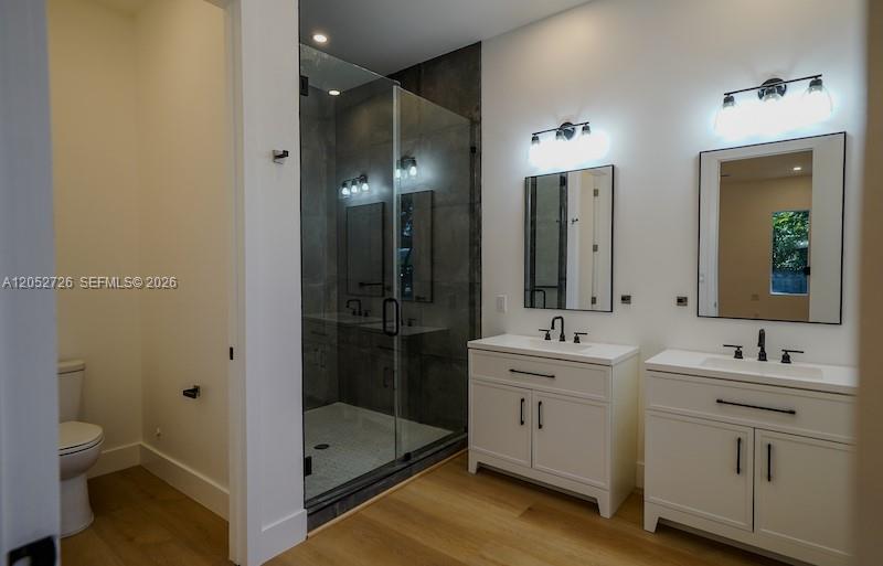 A modern bathroom features a glass-enclosed shower, dual white vanities, and light wood flooring — 112 NW 24th Ct, Miami FL 33125, MIAMI, FL