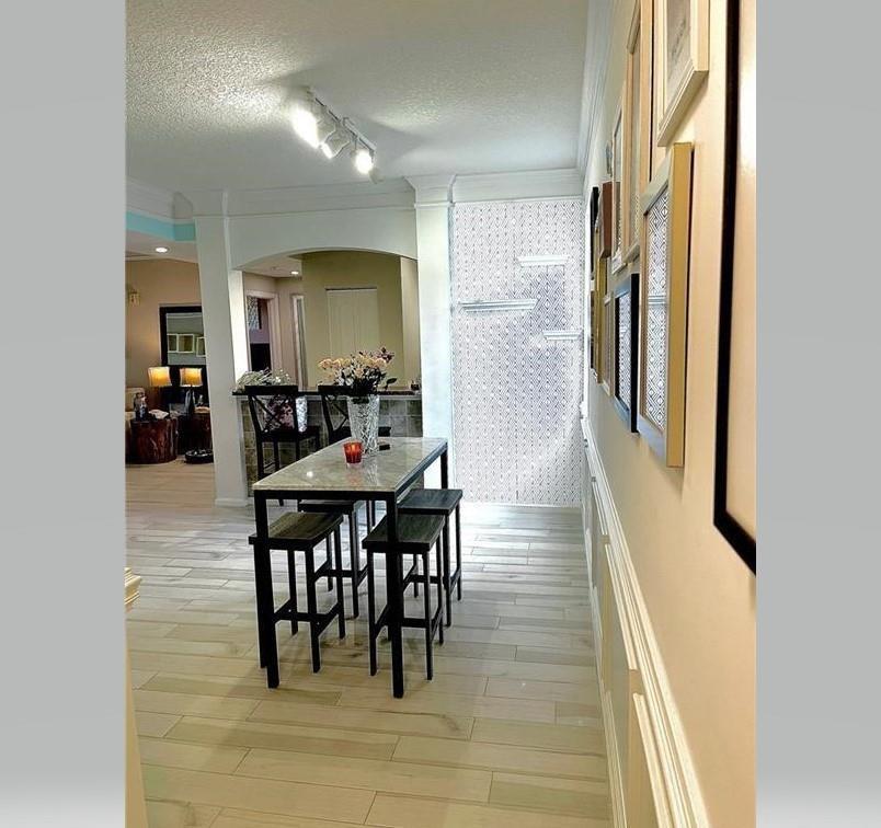 A narrow dining area features a marble-topped table with four stools and a gallery wall — 275 Murcia Drive # 308, Jupiter FL 33458, JUPITER, FL