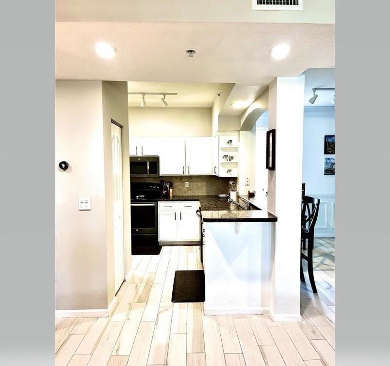 A kitchen with white cabinets, dark countertops, and light wood-look flooring — 275 Murcia Drive # 308, Jupiter FL 33458, JUPITER, FL