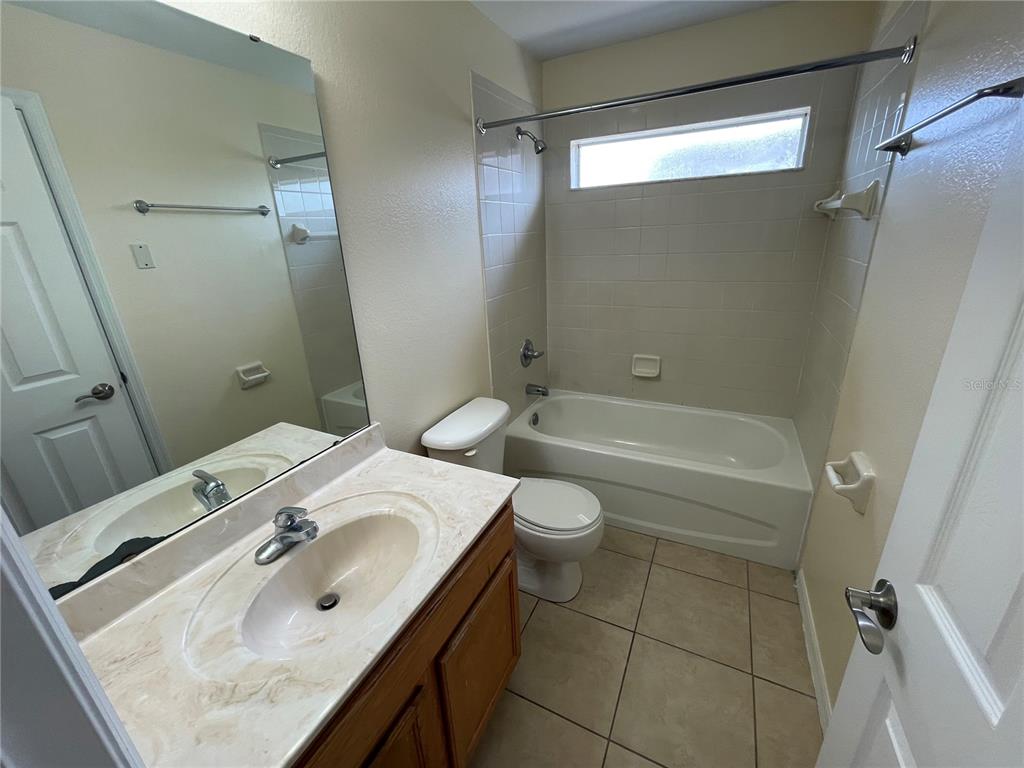 A bathroom features a vanity with a marble countertop, a toilet, and a shower-tub combo — 1406 VISTA DEL LAGO BOULEVARD, DUNDEE, FL