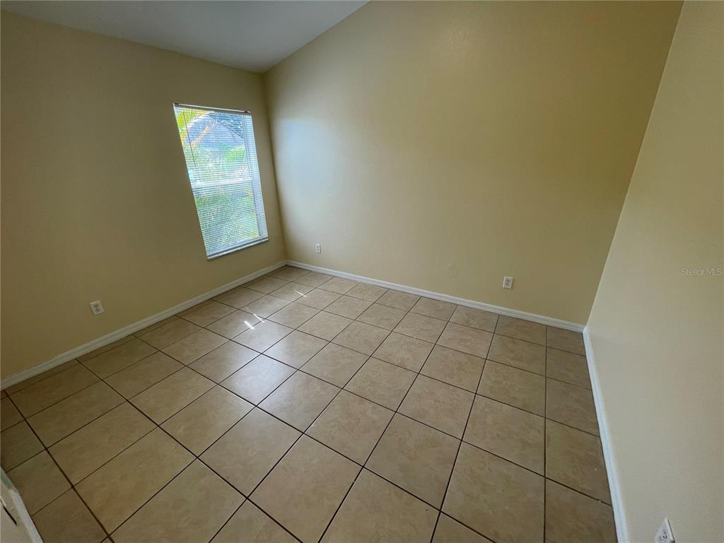 An empty room with beige walls, tile flooring, and a single window with blinds — 1406 VISTA DEL LAGO BOULEVARD, DUNDEE, FL