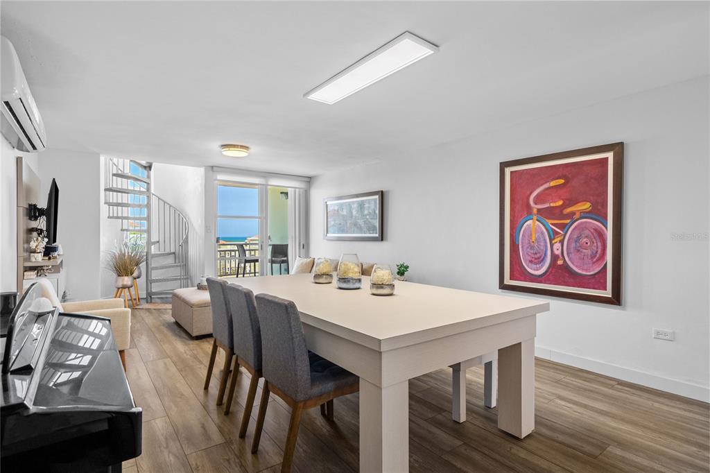 A dining room features a large table, gray chairs, a spiral staircase, and ocean views — Castillos Del Mar LAURO PIÑERO UNIT KC-PH, CEIBA, PR