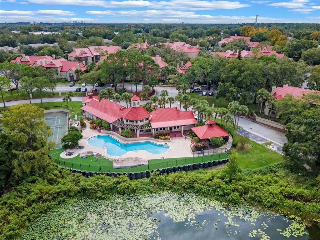 An aerial view of a community pool, tennis court, and clubhouse with red metal roofs — 236 AFTON SQUARE UNIT 305, ALTAMONTE SPRINGS, FL