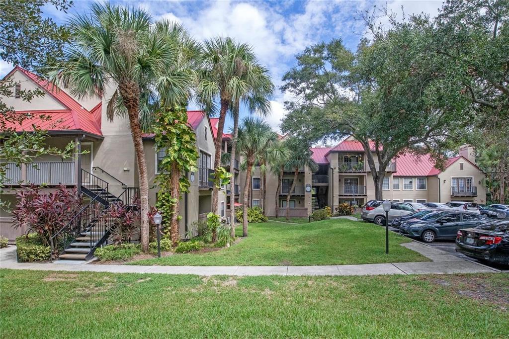 Exterior view of a multi-story apartment complex with red metal roofs and palm trees — 236 AFTON SQUARE UNIT 305, ALTAMONTE SPRINGS, FL
