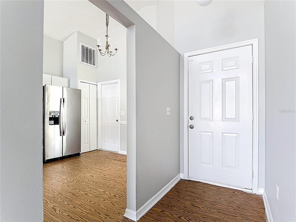 An entryway with wood-look flooring leads into a kitchen featuring stainless steel appliances — 40 COVENTRY COURT, KISSIMMEE, FL