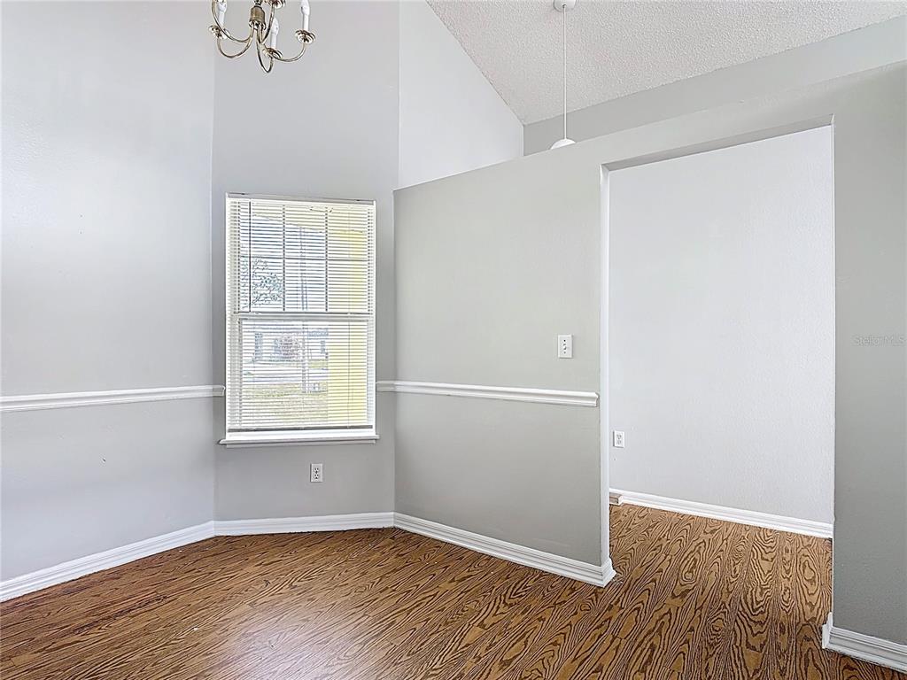 A room with wood-look flooring, light gray walls, a high ceiling, and a window — 40 COVENTRY COURT, KISSIMMEE, FL