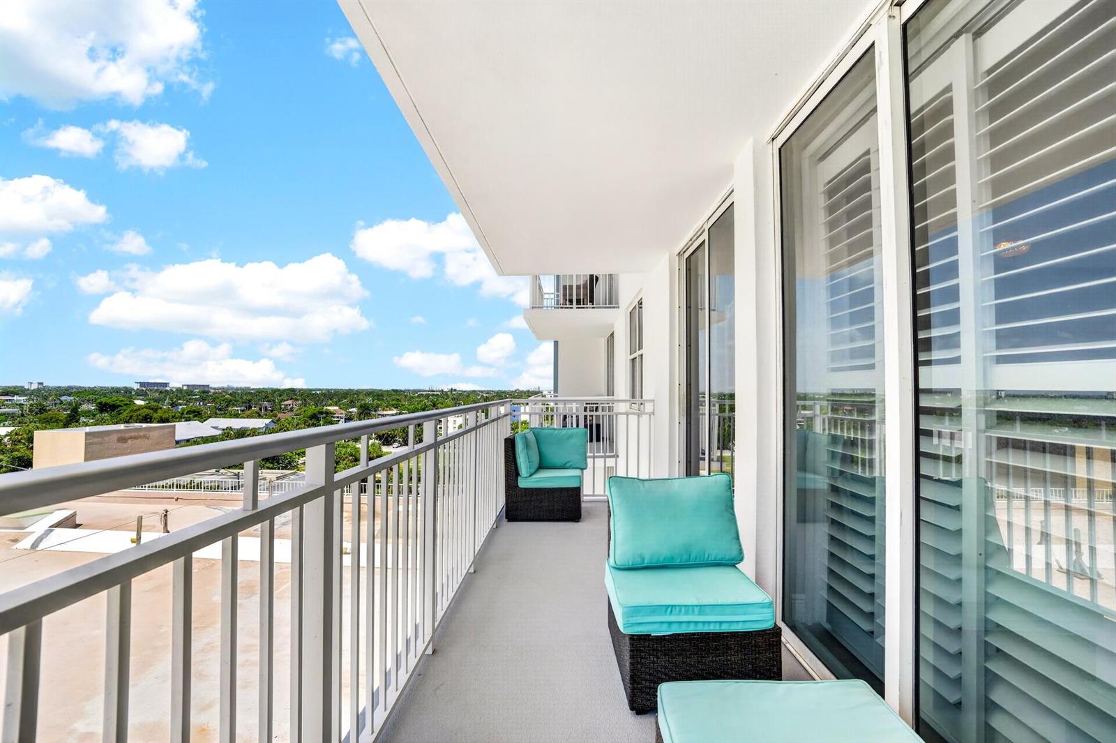 A balcony with a metal railing features two wicker chairs with bright turquoise cushions — 101 Briny Avenue # 808, Pompano Beach FL 33062, POMPANO BEACH, FL
