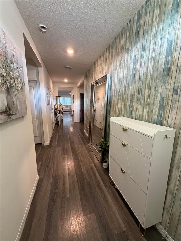 A hallway features wood-look flooring, a patterned accent wall, a floor mirror, and a shoe cabinet — 1677 THREE BARS ROAD, KISSIMMEE, FL