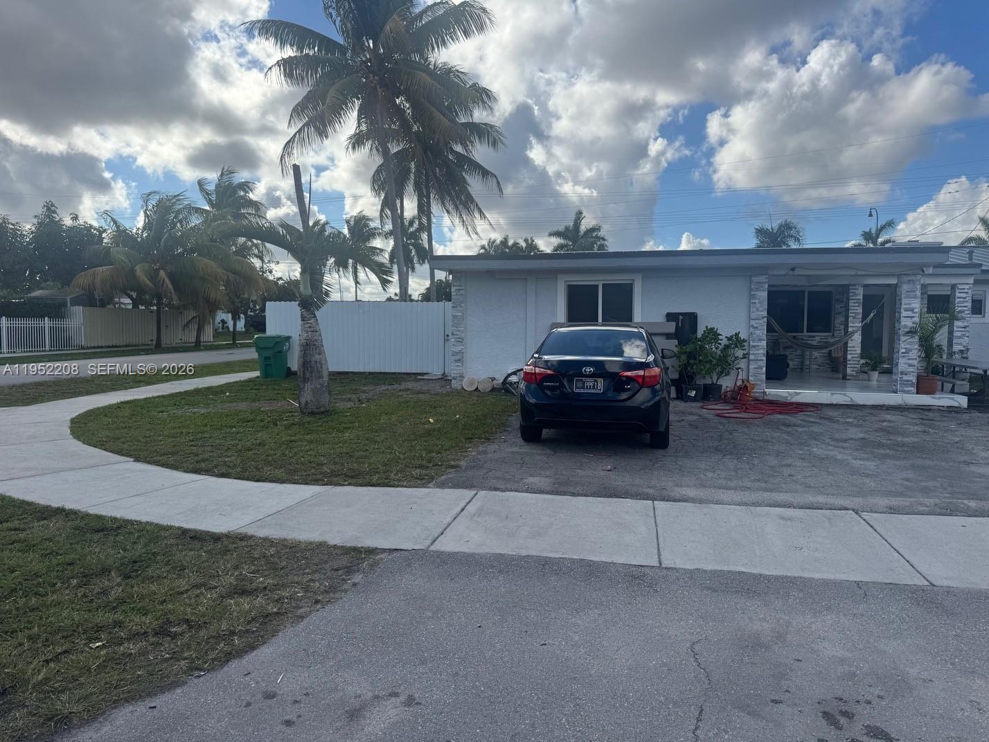 A black sedan is parked in the driveway of a single-story house with palm trees — 19700 NW 6th Pl, Miami Gardens FL 33169, MIAMI GARDENS, FL