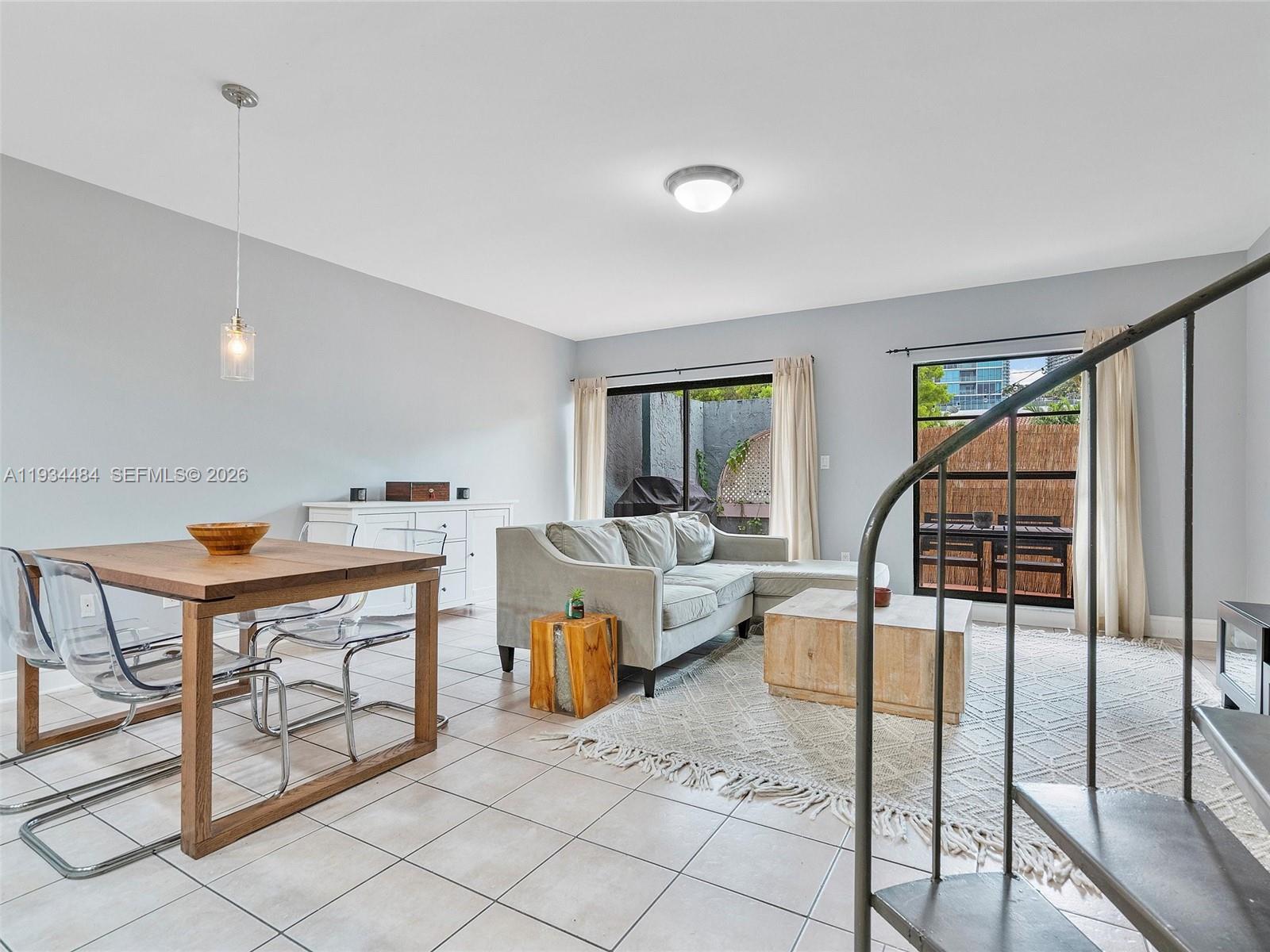 A living and dining area features tile floors, a spiral staircase, and a sliding glass door — 515 NE 38th St # 10, Miami FL 33137, MIAMI, FL