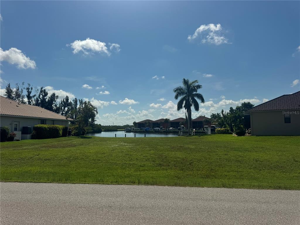 A grassy vacant lot sits between two houses, overlooking a canal with docked boats — 3524 TERIN COURT, PUNTA GORDA, FL