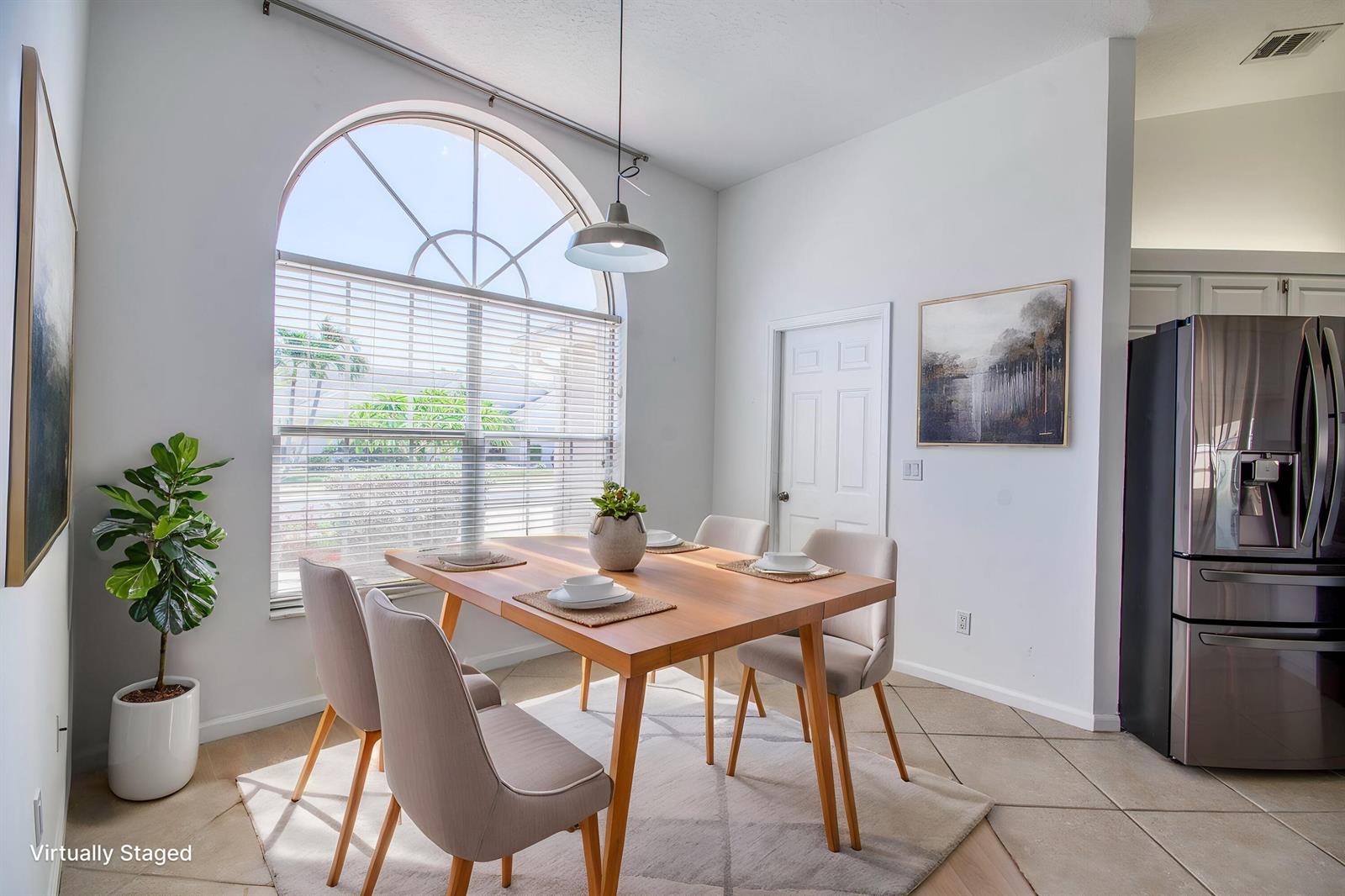A dining area features a wooden table, four chairs, a large arched window, and tile flooring — 252 Moccasin Trail W, Jupiter FL 33458, JUPITER, FL