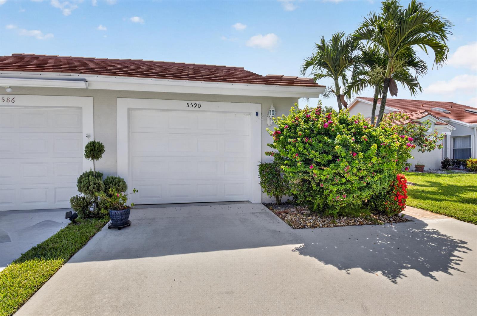 A white garage door is centered on the exterior of a single-story residential building — 5590 Royal Lake Circle, Boynton Beach FL 33437, BOYNTON BEACH, FL
