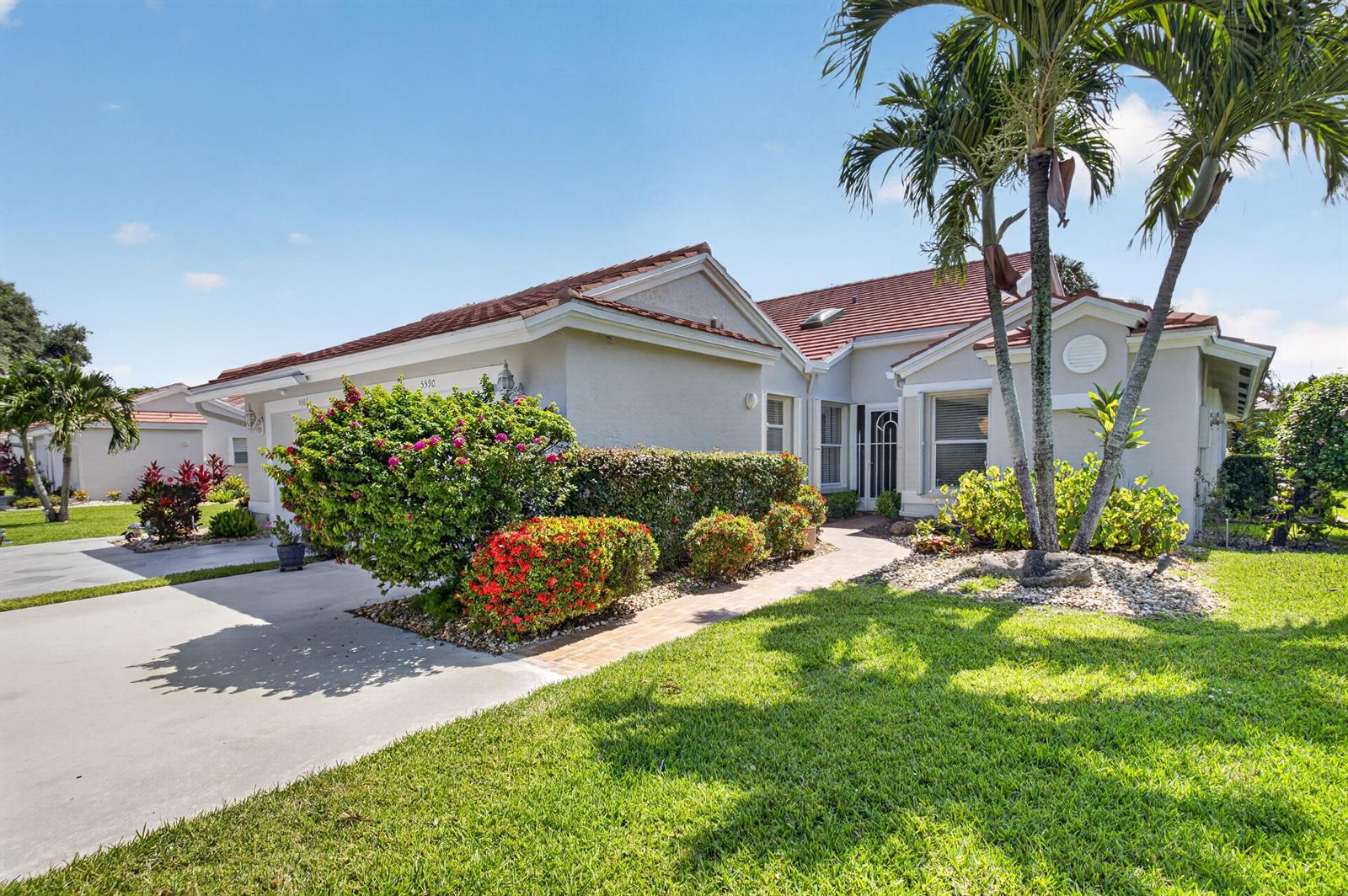 A single-story house with a tile roof, concrete driveway, and palm trees in the front yard — 5590 Royal Lake Circle, Boynton Beach FL 33437, BOYNTON BEACH, FL