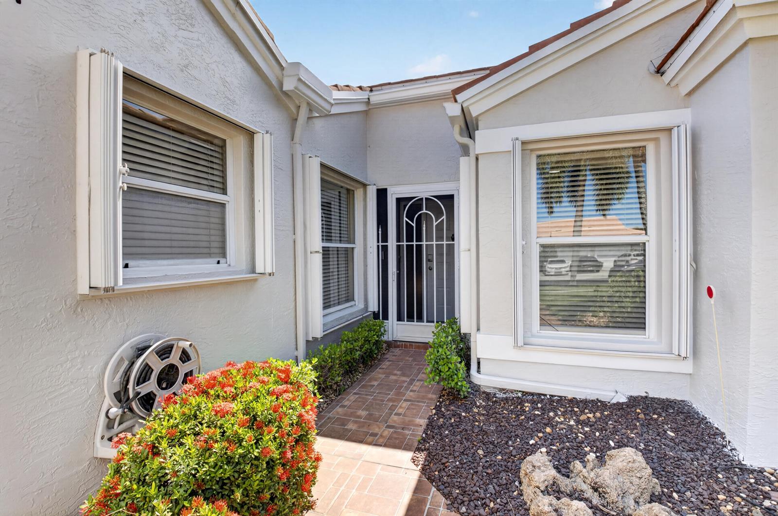 A paved walkway leads to the front entrance of a house with light-colored stucco walls — 5590 Royal Lake Circle, Boynton Beach FL 33437, BOYNTON BEACH, FL