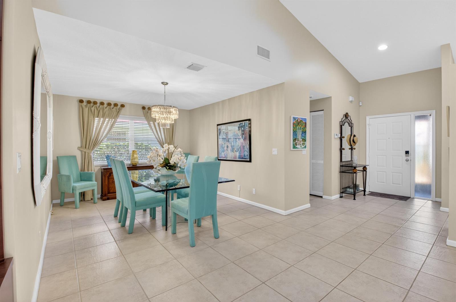A dining room with a glass table, teal chairs, and a chandelier on tiled floors — 5590 Royal Lake Circle, Boynton Beach FL 33437, BOYNTON BEACH, FL