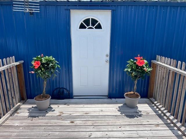 A white door with a semi-circular window is centered on a blue metal-sided exterior wall — 45506 MAGNOLIA STREET, PAISLEY, FL