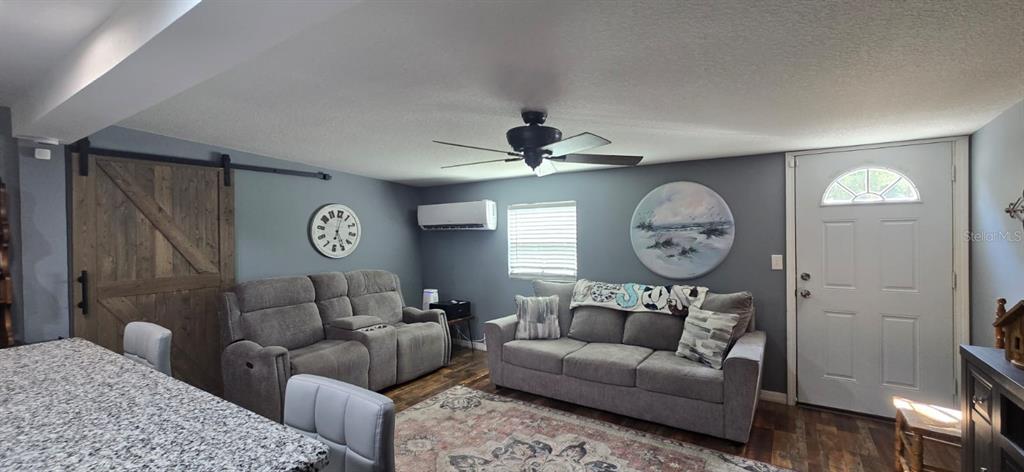 A living room features gray walls, a sliding barn door, two sofas, and a ceiling fan — 45506 MAGNOLIA STREET, PAISLEY, FL